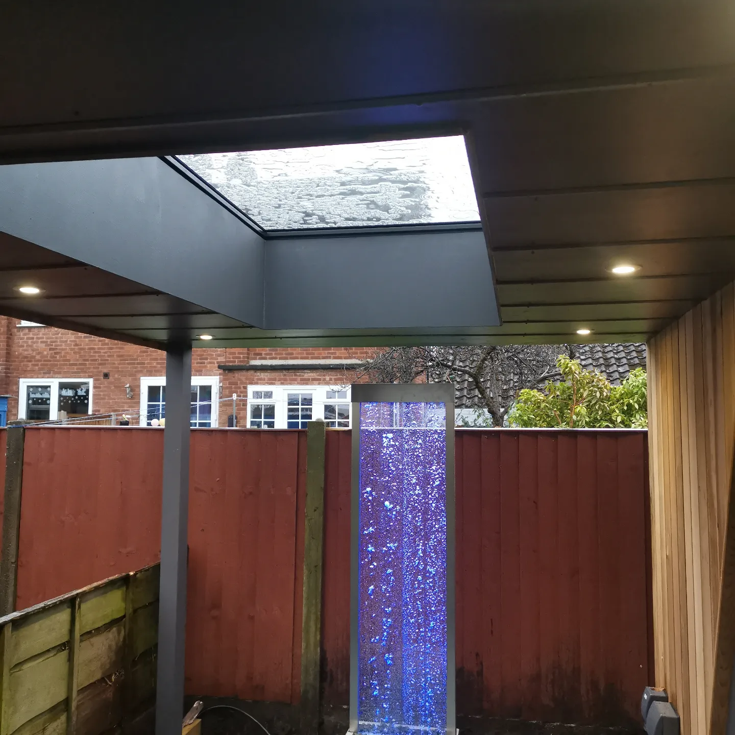 Outdoor garden awning with lights and water feature in Stockport by Prima Construction
