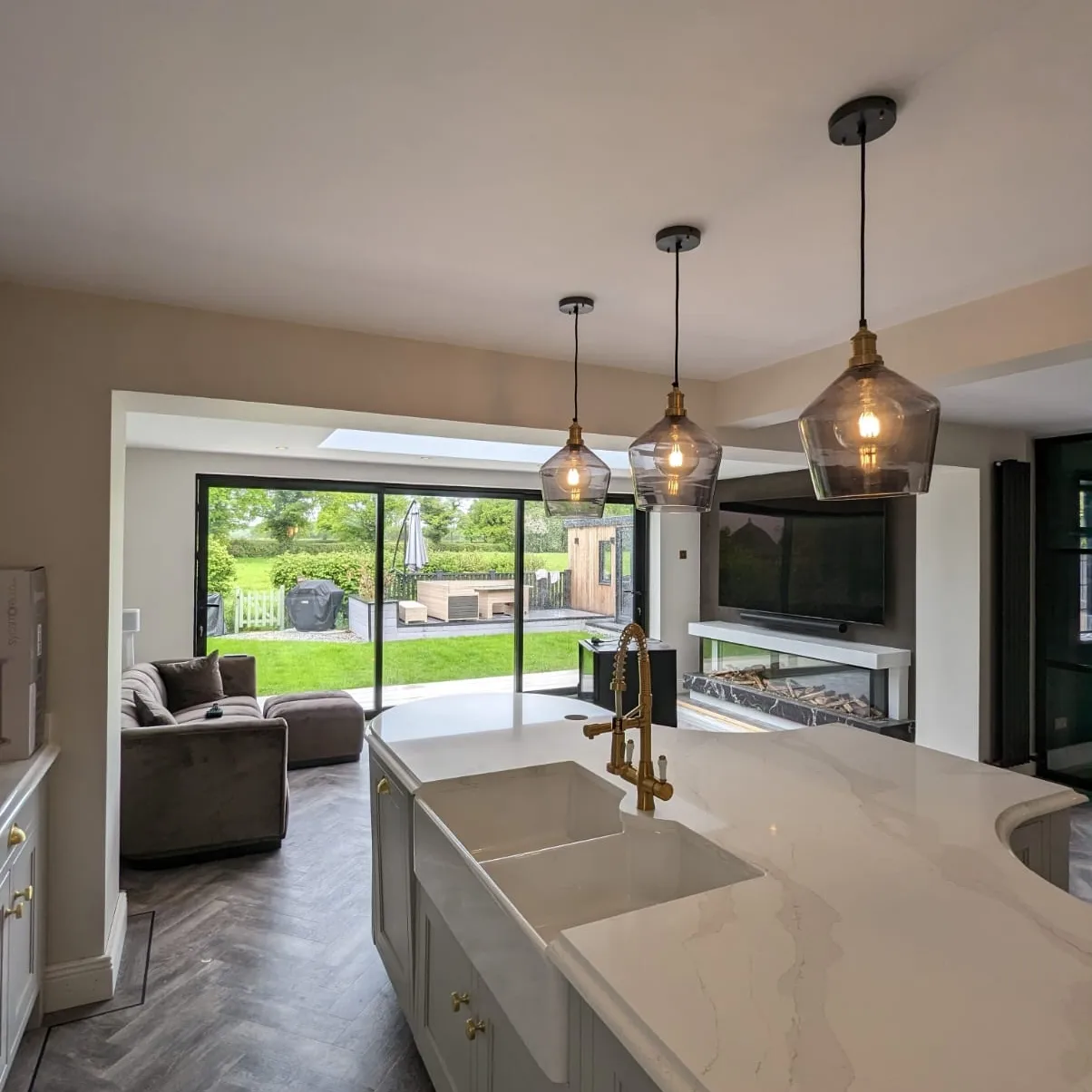 A large open plan living kitchen space with quartz countertops and butler sink installed by Prima Construction in Stockport