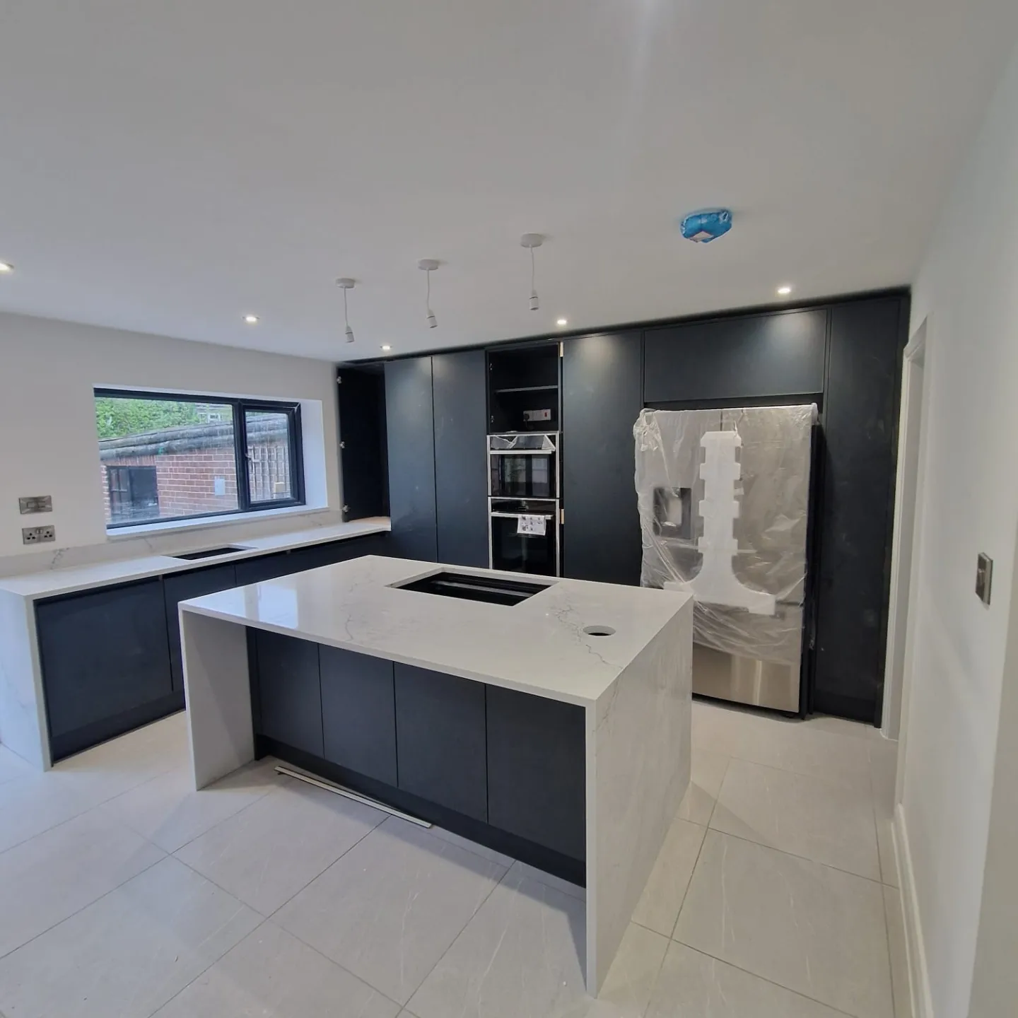 Matte black kitchen with island installed by Prima Construction